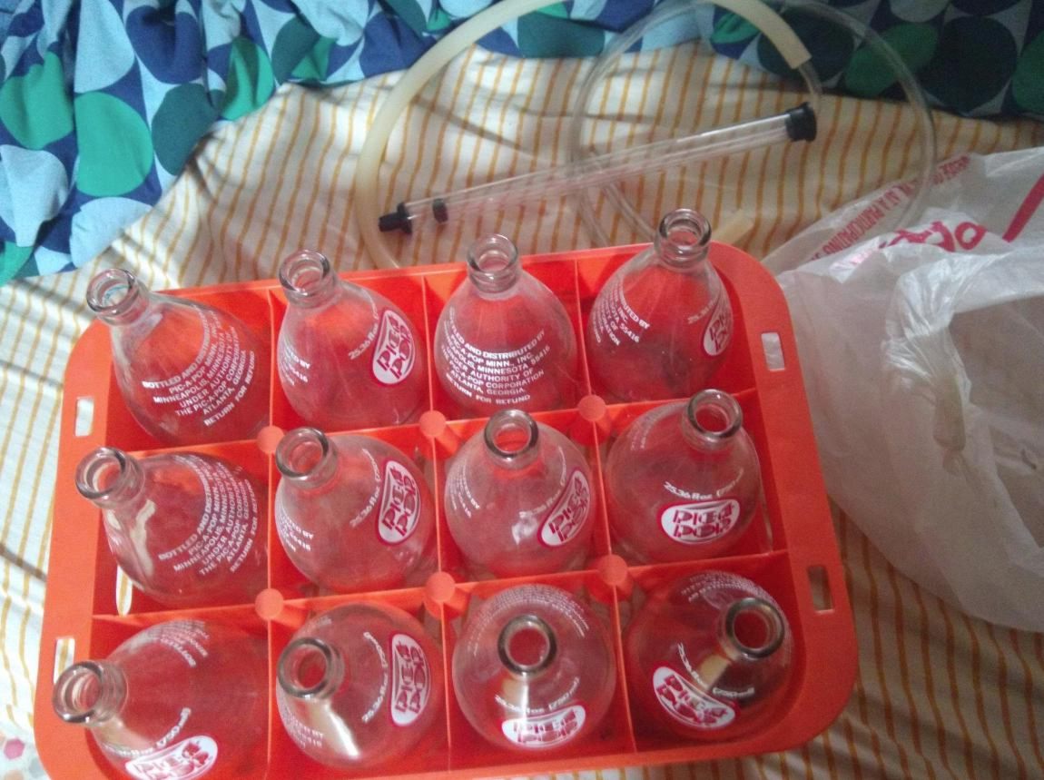 photo of an autosiphon and a brigt orange plastic crate of 750ml art-deco "pic-a-pop" clear glass bottles