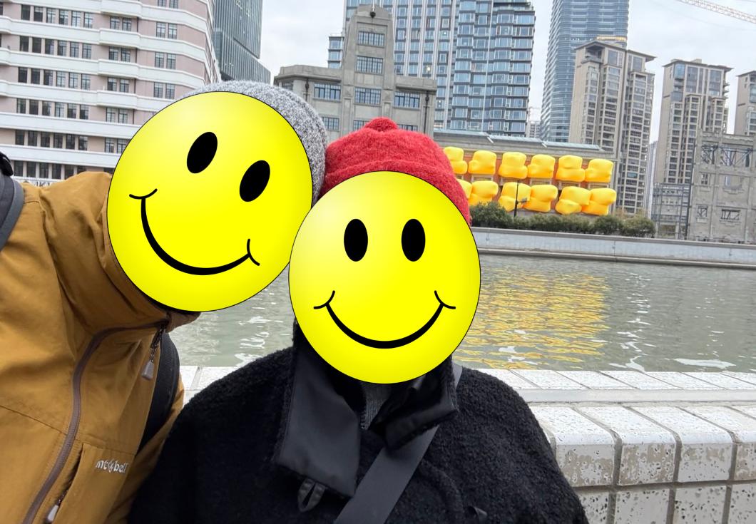 My brother and his wife posing by the river in  Shanghai while wearing their fuzzy little hats 